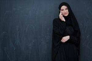 Young muslim businesswoman in traditional clothes or abaya using smartphone