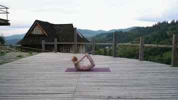 Yoga femme sur terrasse en bois et montagnes video
