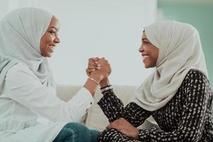 African woman arm wrestling conflict concept, disagreement and confrontation wearing traditional islamic hijab clothes. Selective focus photo
