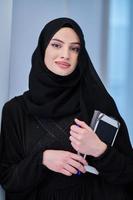 Young Arab businesswoman in traditional clothes or abaya with tablet computer photo