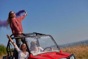 excited people having fun enjoying beautiful sunny day holding colorful torches while driving a off road buggy car photo