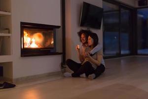 happy multiethnic couple sitting in front of fireplace photo