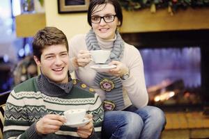 Young romantic couple sitting and relaxing in front of fireplace at home photo