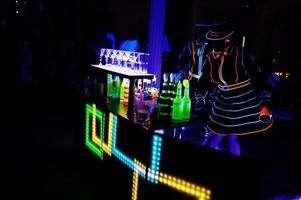 Professional barman and led light show. Silhouette of modern bartender shaking drink at night cocktail bar. photo