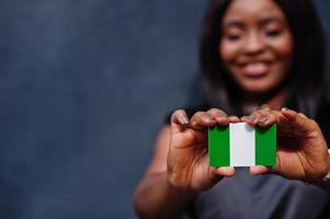 mujer africana sostiene una pequeña bandera de nigeria en las manos. foto