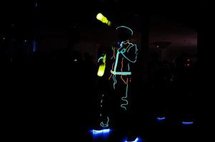 Professional barman and led light show. Silhouette of modern bartender shaking drink at night cocktail bar. photo