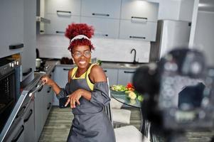 African american woman filming her blog broadcast about healthy food at home kitchen, bakes a cake in the oven. photo