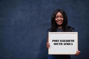 African woman hold white board with Port Elizabeth South Africa inscription. Most populous city in Africa concept. photo