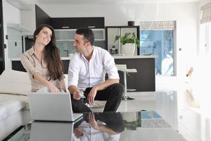 una pareja alegre se relaja y trabaja en una computadora portátil en una casa moderna foto