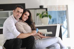 una pareja alegre se relaja y trabaja en una computadora portátil en una casa moderna foto