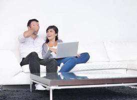 una pareja alegre se relaja y trabaja en una computadora portátil en una casa moderna foto