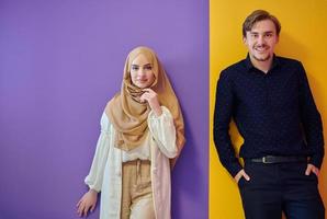 Portrait of happy young muslim couple standing isolated on colorful background photo