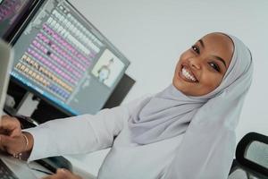 Young Afro-American modern Muslim businesswoman wearing a scarf in a creative bright office workplace with a big screen. photo