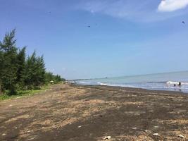 A beach in the north of Java with dark brown sand. photo