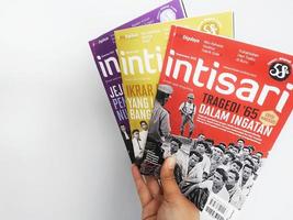 A hand is holding some Intisari magazines photo