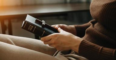 una mujer rezando sosteniendo una biblia sagrada y rezando a dios. foto