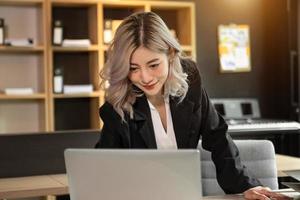 hermosa mujer de negocios asiática escribiendo una computadora portátil y una tableta colocadas en la mesa de la oficina foto