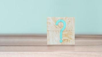 Question Mark word in wooden cube blocks on wood table with cyan wall background. photo