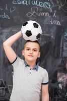 niño feliz sosteniendo un balón de fútbol en la cabeza foto