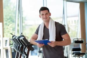 entrenador con portapapeles de pie en un gimnasio brillante foto