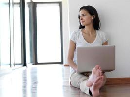 relaxed young woman at home working on laptop computer photo