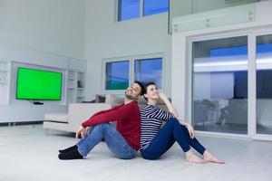 young couple sitting with back to each other on floor photo