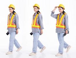 Mujer contratista de ingeniero de carrera mixta de longitud completa de 20 años, caminando hacia adelante izquierda derecha, use guantes de seguridad vastos. Los soportes femeninos de la oficina sienten una sonrisa feliz sobre un fondo blanco aislado foto