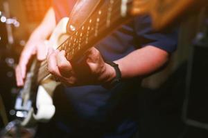 close up hand young man playing electric guitar at recording studio rehearsal base. rock music band. photo