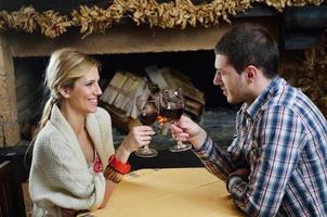 Young romantic couple sitting on sofa in front of fireplace at home photo