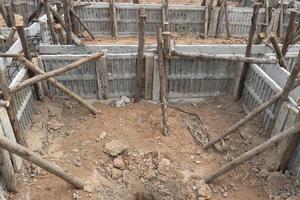 encofrado de bloques para vigas de casas con soporte de troncos de madera. construcción de los cimientos de la casa en el suelo durante el día. foto