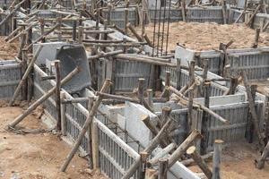 encofrado de bloques para vigas de casas con soporte de troncos de madera. construcción de los cimientos de la casa en el suelo durante el día. foto