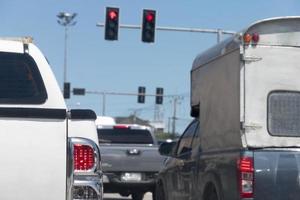 Rear side of pick up white car stops on the road with turn on brake light. Traffic congestion during working hours or during rush hours. Traffic light pole ready to go to the red signal at front. photo