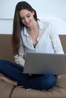 mujer joven relajada en casa trabajando en una computadora portátil foto