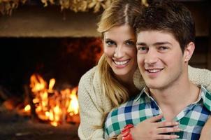 Young romantic couple sitting on sofa in front of fireplace at home photo