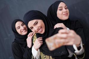 muslim women taking selfie picture in front of black chalkboard photo