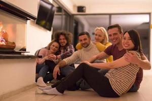 multiethnic couples sitting in front of fireplace photo