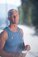 senior jogging man drinking fresh water from bottle photo