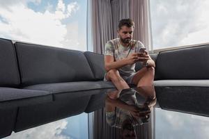 joven casual usando un teléfono móvil en casa foto