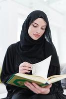 young muslim woman reading Quran at home photo