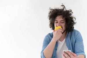 young man eating apple and using a mobile phone  at home photo