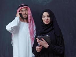 muslim couple using modern technology in front of black chalkboard photo