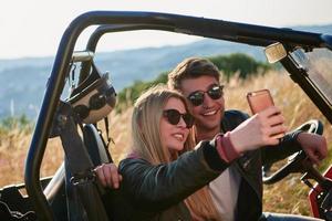 pareja disfrutando de un hermoso día soleado tomando una foto selfie mientras conduce un buggy todoterreno