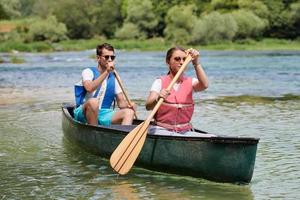 friends are canoeing in a wild river photo