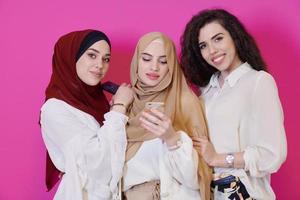 mujeres musulmanas que usan teléfonos móviles aisladas en rosa foto