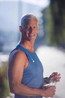 senior jogging man drinking fresh water from bottle photo