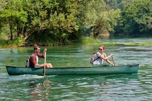 friends are canoeing in a wild river photo