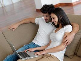 relaxed young couple working on laptop computer at home photo