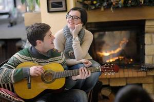 Young romantic couple sitting on sofa in front of fireplace at home photo