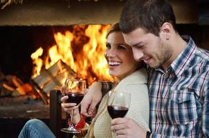 Young romantic couple sitting on sofa in front of fireplace at home photo