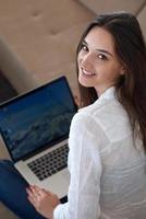 relaxed young woman at home working on laptop computer photo